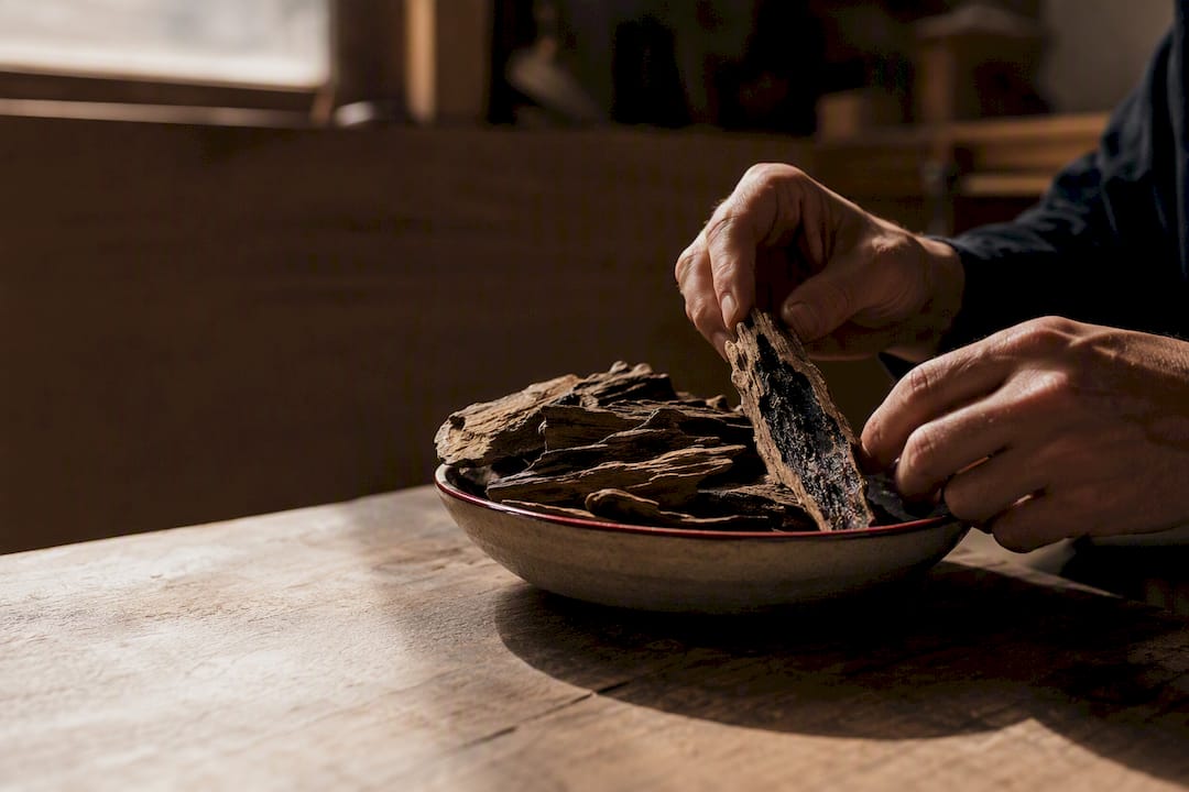 Donkere agarwood-chips vol hars in een keramisch schaaltje